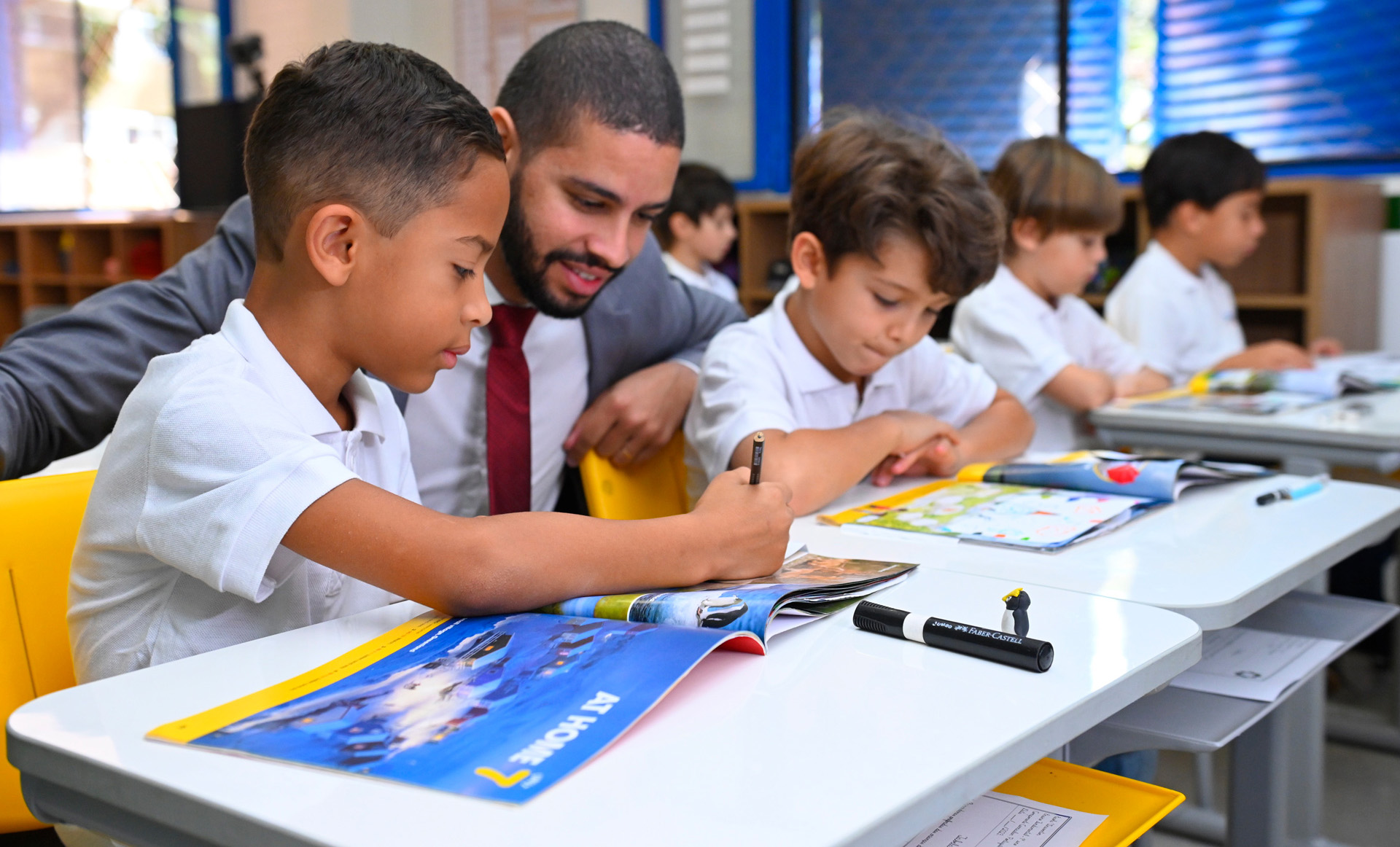 Professor acompanhando atividade dos alunos em sala de aula